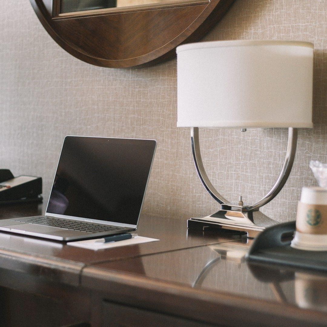 Schreibtisch mit Laptop und Tischleuchte im Zimmer