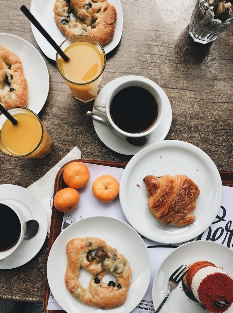 Gedeckter Frühstückstisch mit Kaffee, Orangensaft, Croissant und Gebäck