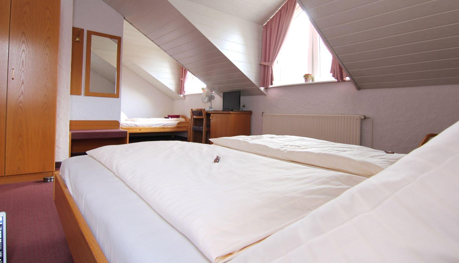 Doppelzimmer unter dem Dach mit Doppelbett, Kleiderschrank und Fenster